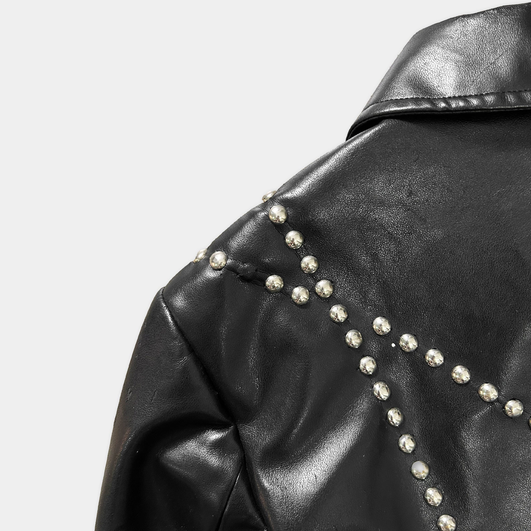 A close-up view of a black leather jacket with silver studs on the shoulder and collar area.