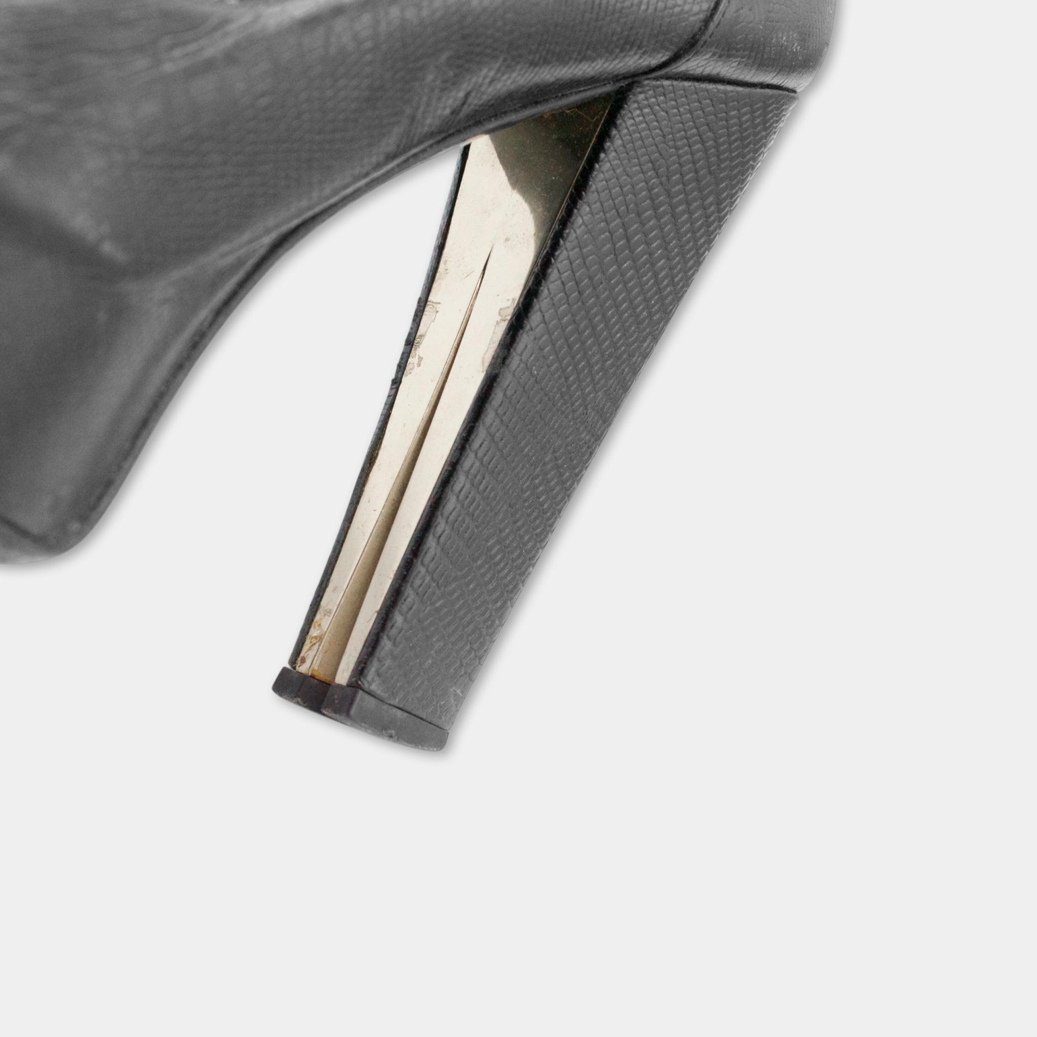 A close-up view of a black high-heeled shoe, focusing on the heel and toe area.