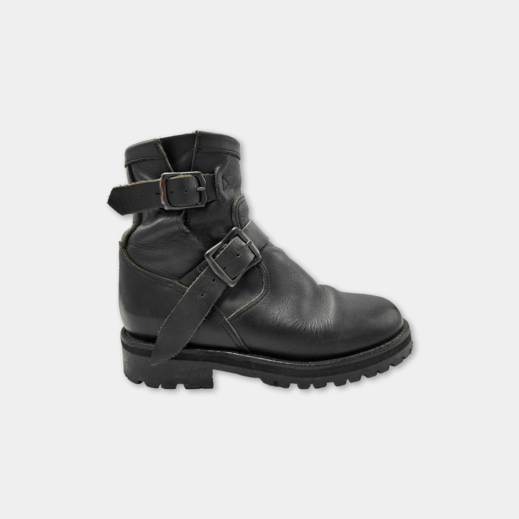 A black leather boot with a buckle detail and a rugged sole.