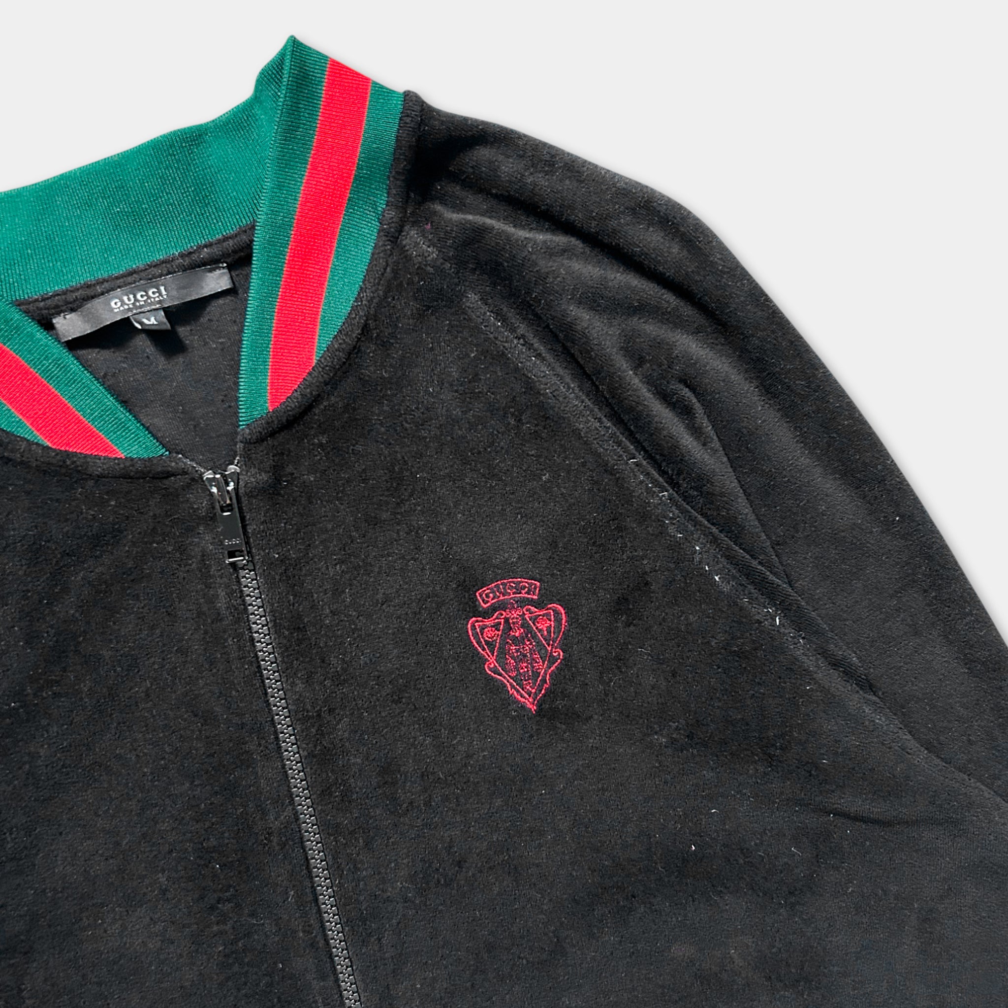 A black Gucci jacket with a red and green striped collar and a red Gucci logo on the front.