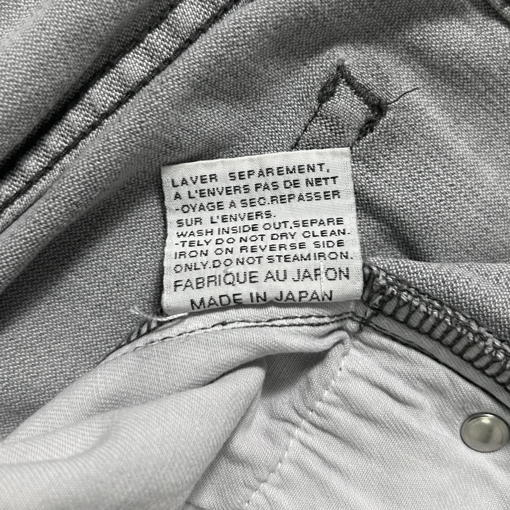 a close-up view of a label on a pair of gray jeans, providing information about the jeans' care instructions.