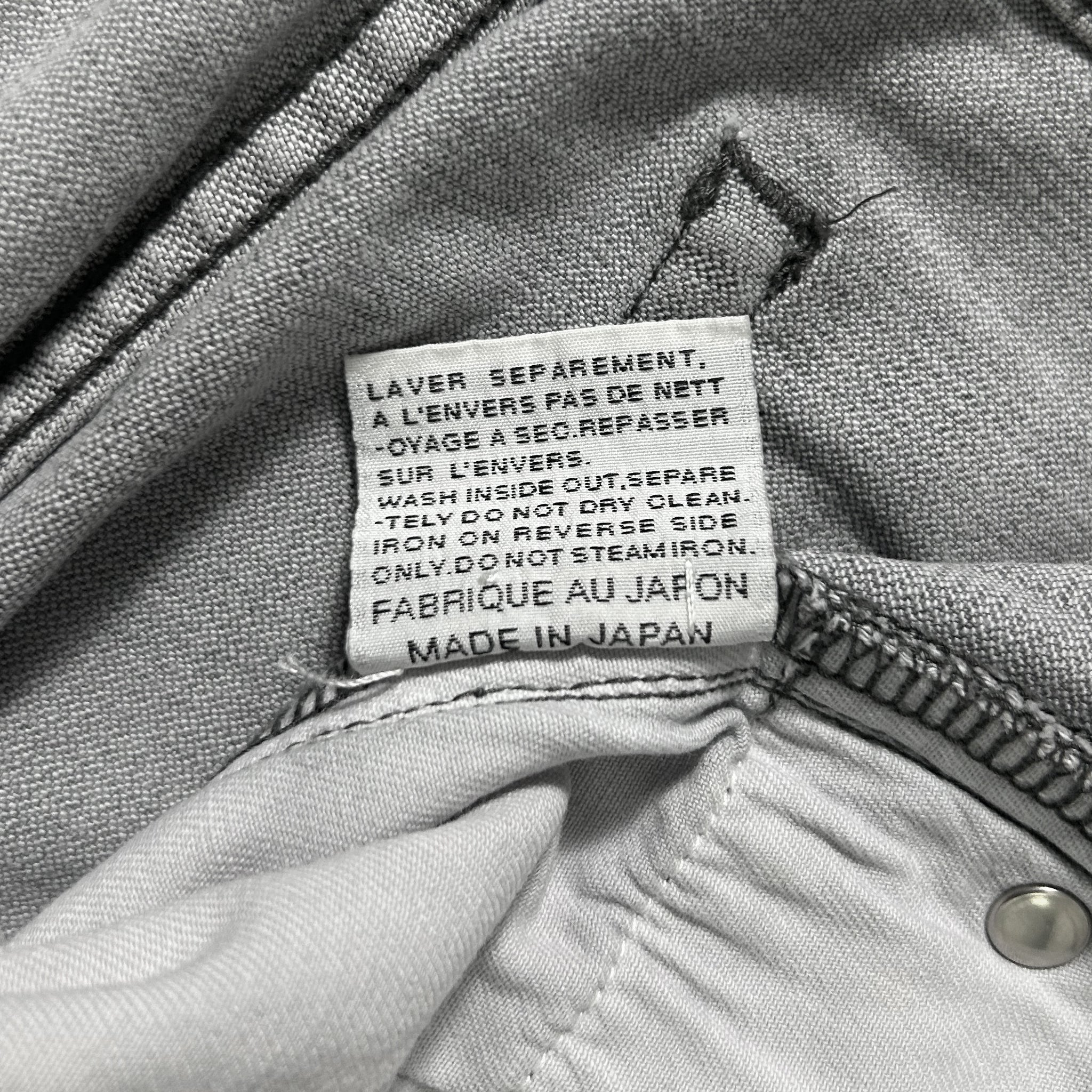 a close-up view of a label on a pair of gray jeans, providing information about the jeans' care instructions.