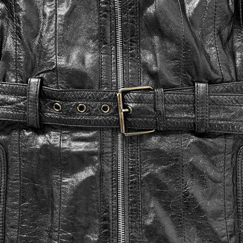 A close-up view of a black leather jacket with a metal buckle and a zipper.