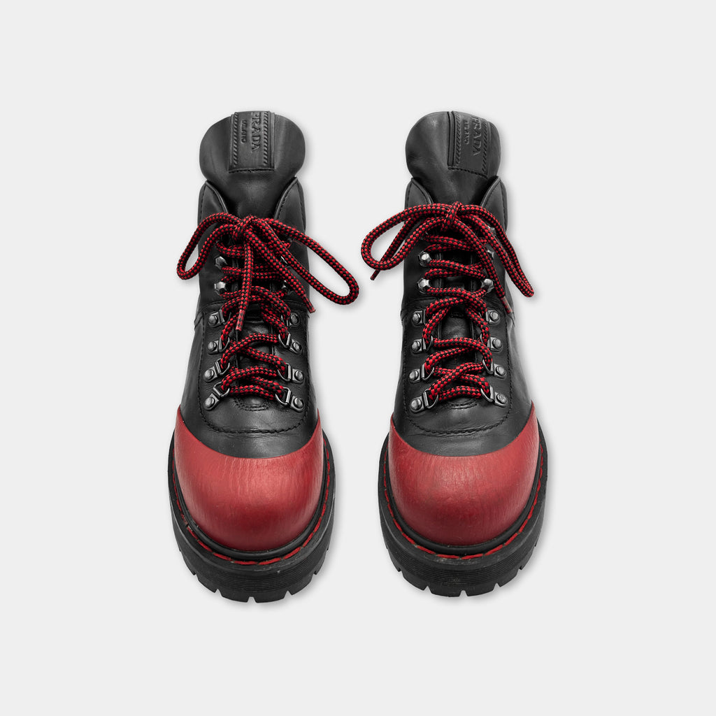 A pair of black and red hiking boots with red laces and a red sole, positioned side by side against a white background.