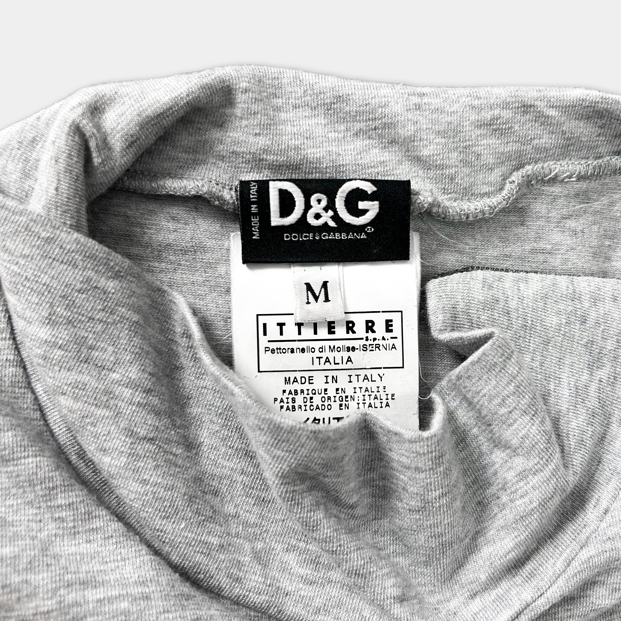 A close-up of a gray t-shirt with a D&G logo and a label indicating the brand and country of production.