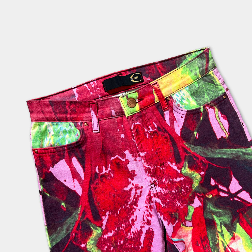 A pair of colorful, patterned jeans with a vibrant mix of red, green, and yellow colors.