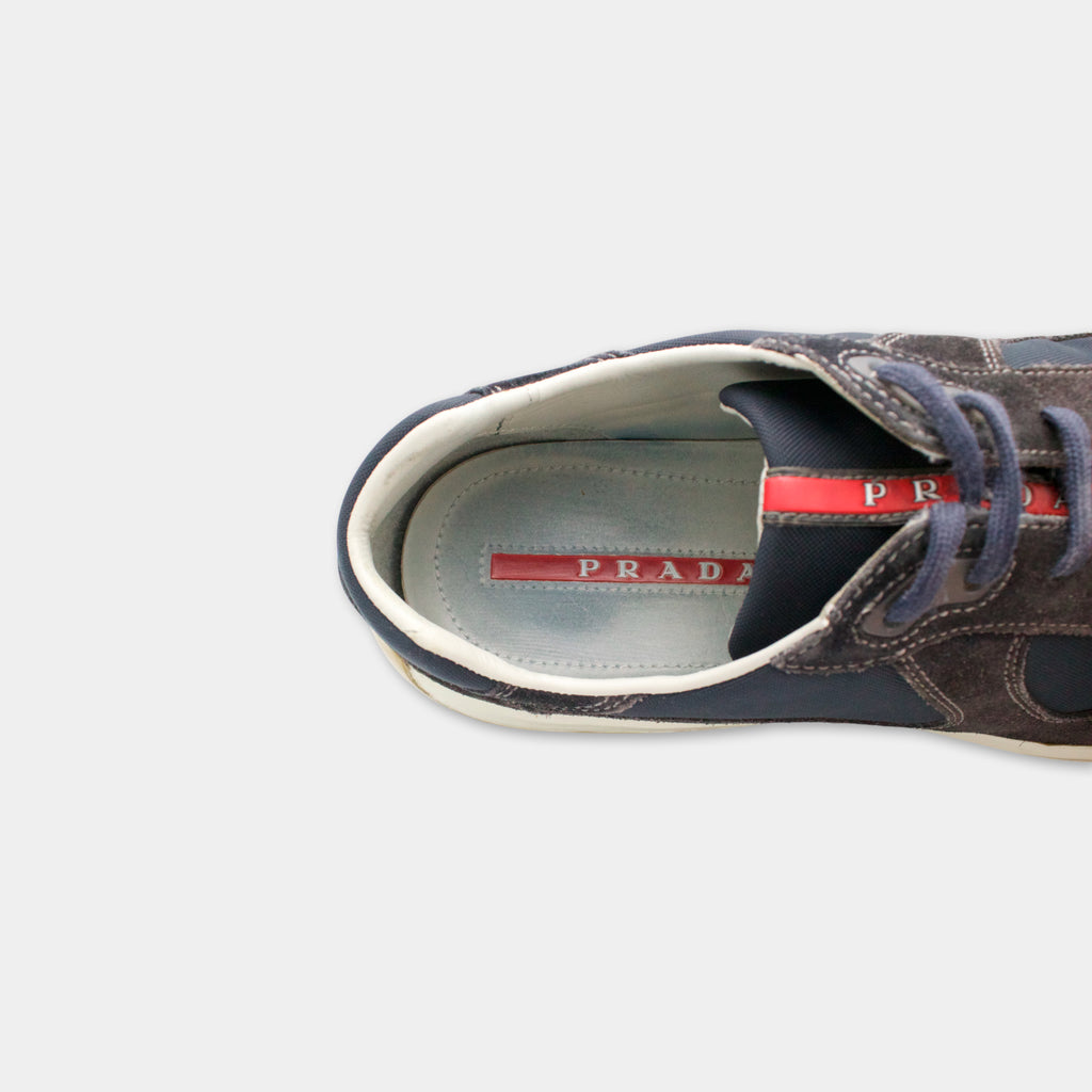 A close-up view of a Prada sneaker, showing the upper part of the shoe with the brand name visible on the sole.