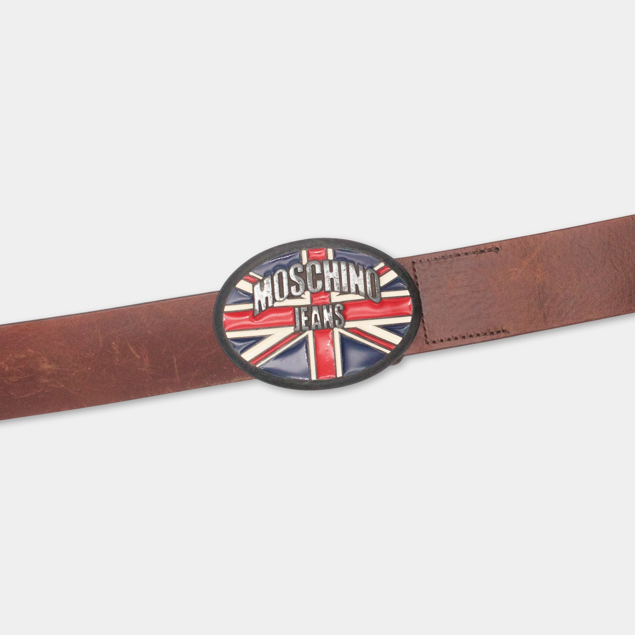 A brown leather belt with a round metal buckle featuring the Moschino Jeans logo.