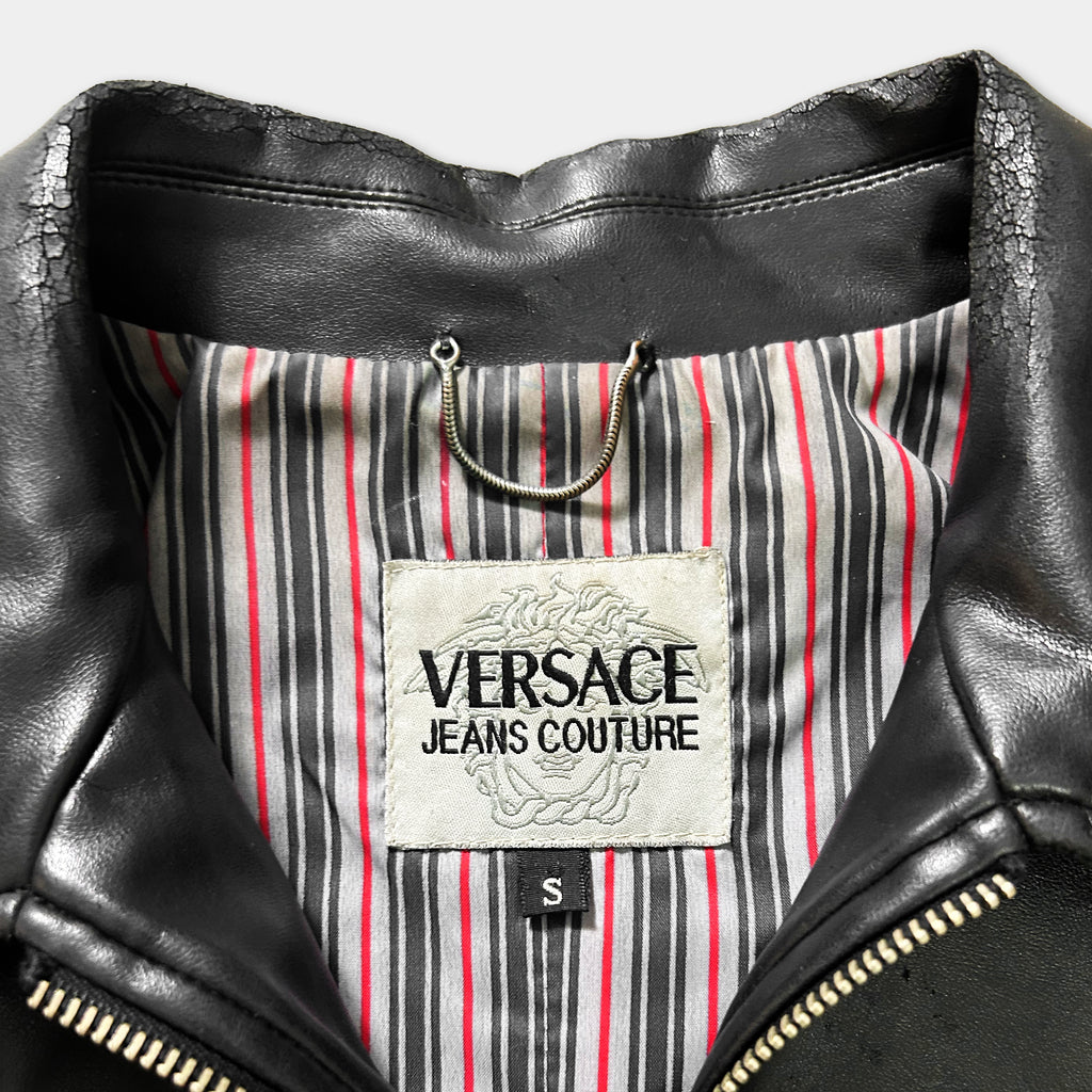 a close-up view of a black leather jacket with a Versace Jeans Couture label on the inside lining.
