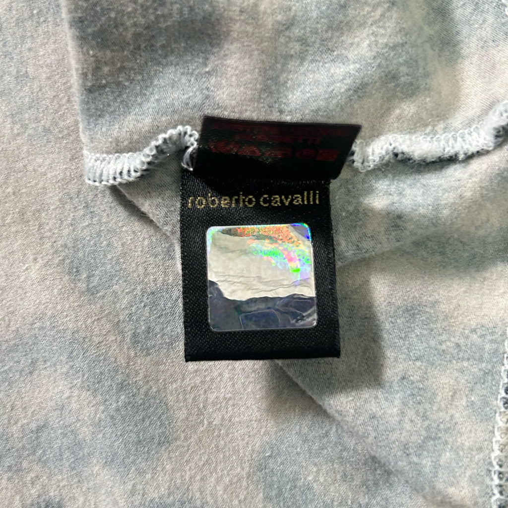 a close-up view of a fabric label with text and a small square image on it, attached to a piece of fabric.