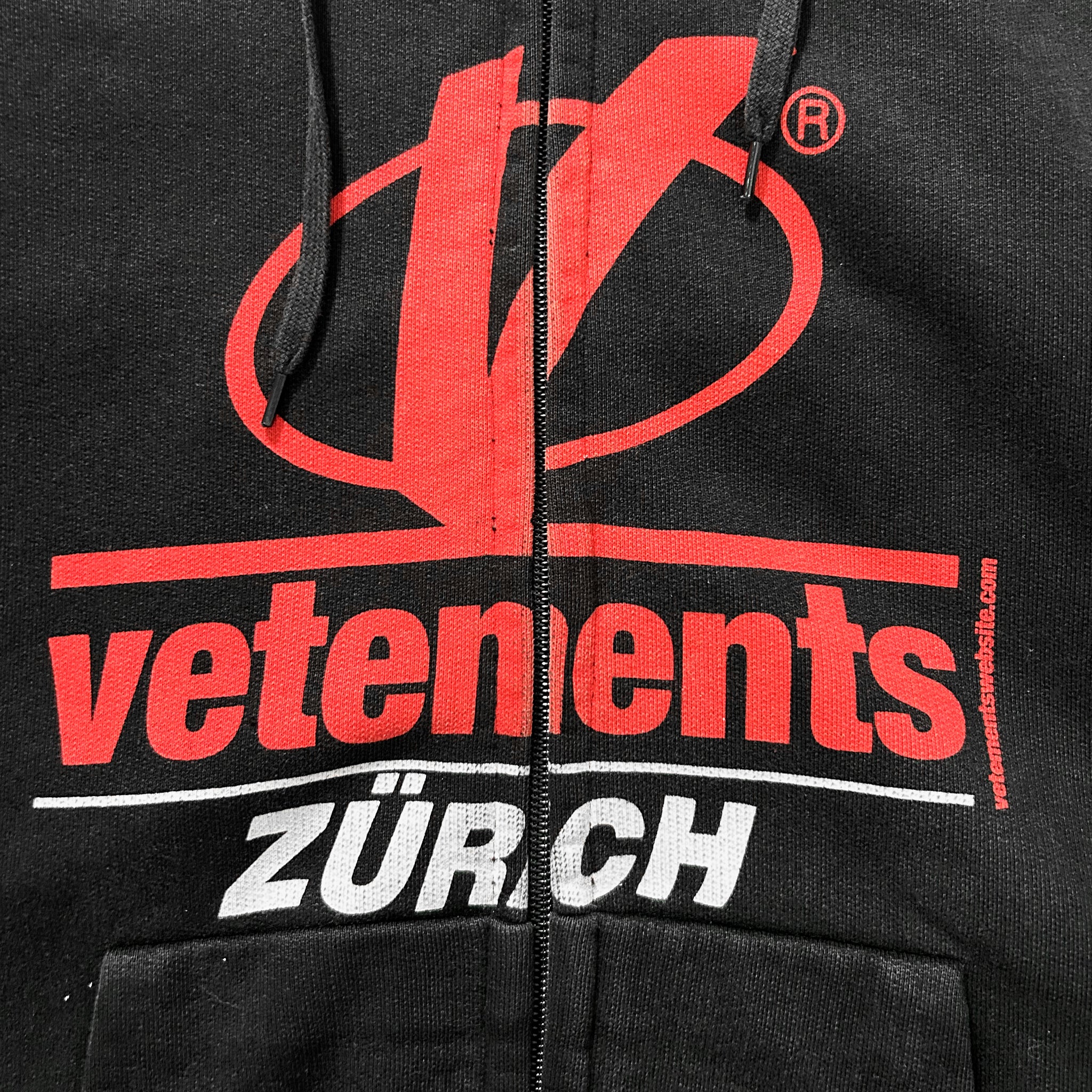 a close-up view of a black jacket with a red logo and text printed on it.