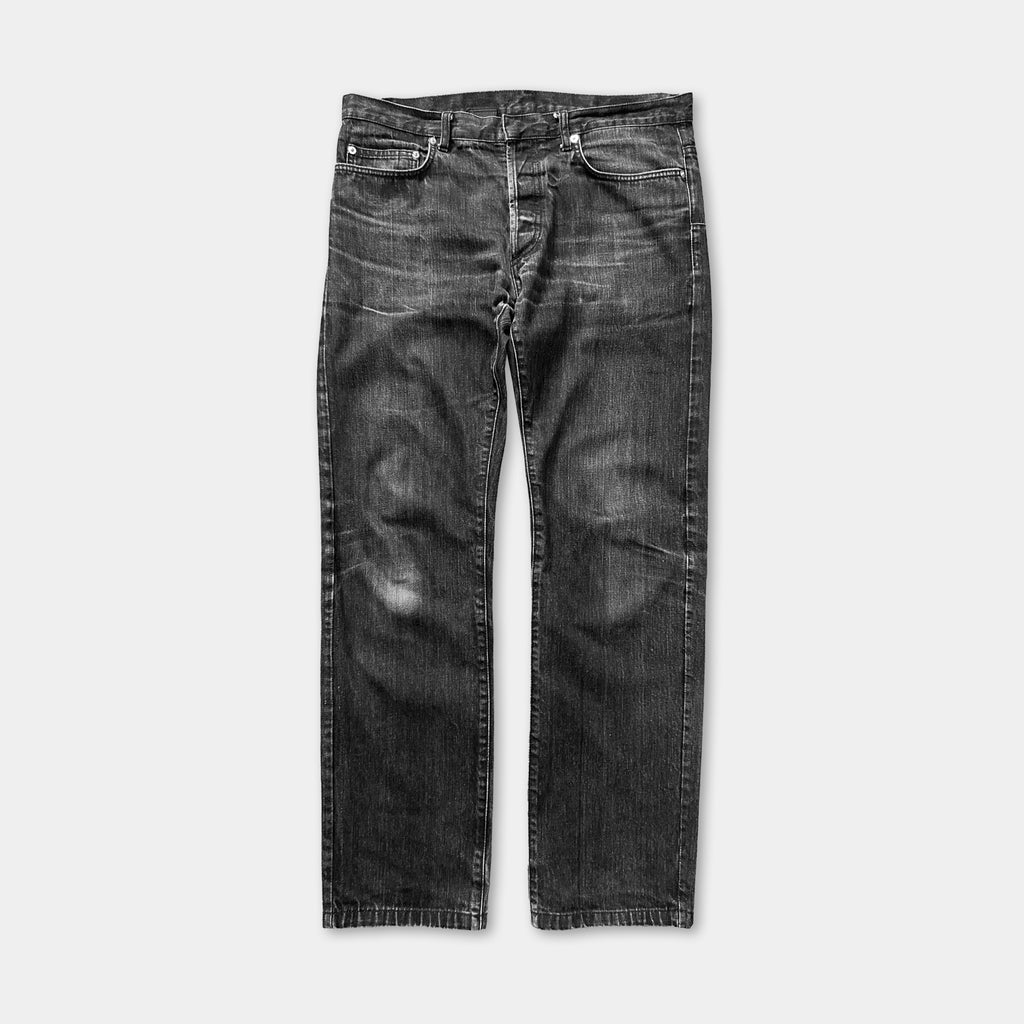 A pair of black, well-worn jeans with visible signs of wear and tear.