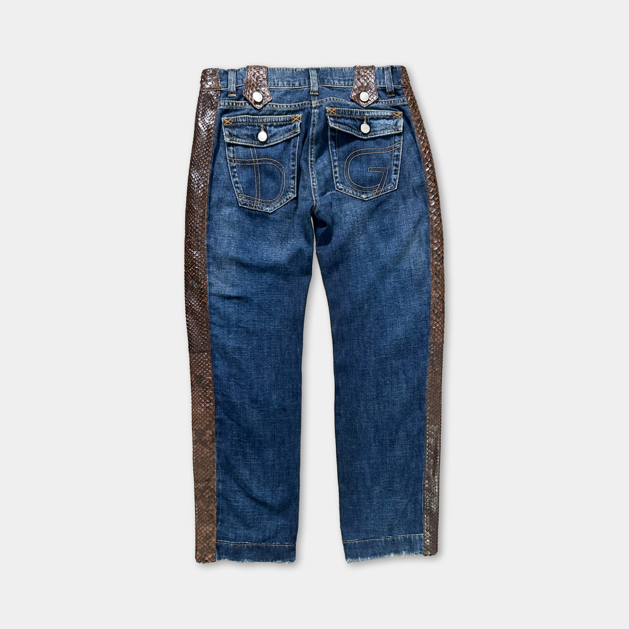 A pair of blue jeans with a brown decorative stripe running along the bottom edge.