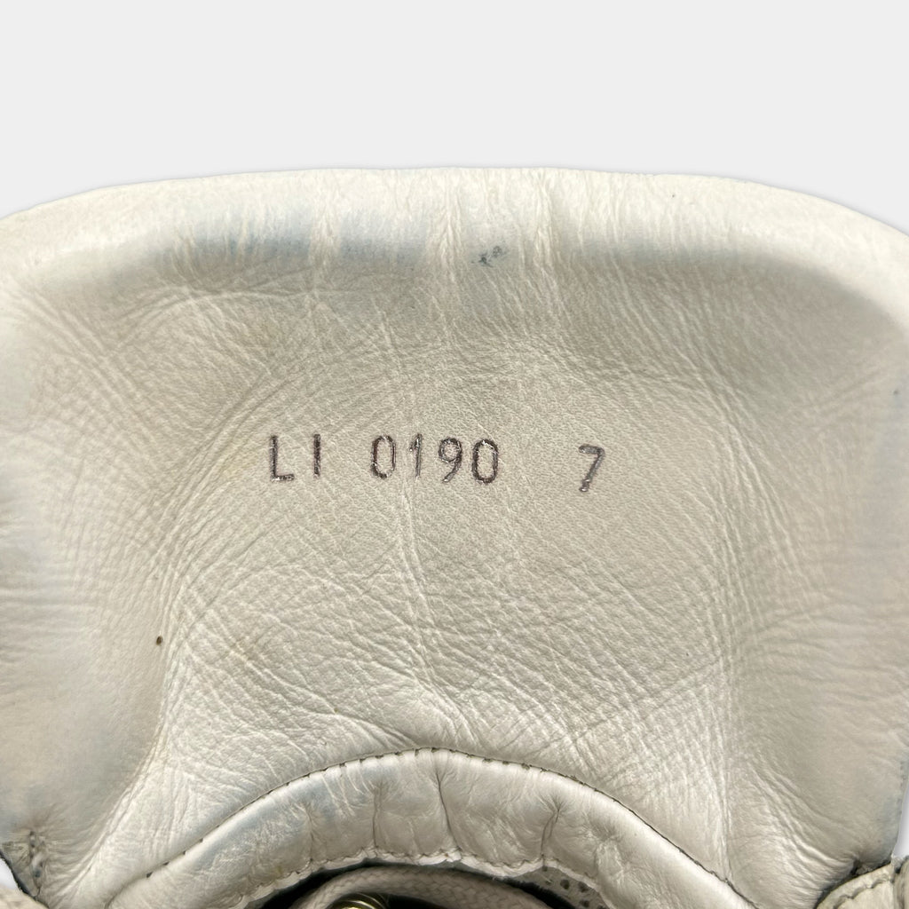 the inside of a white shoe, with the brand name and model number printed on the leather.