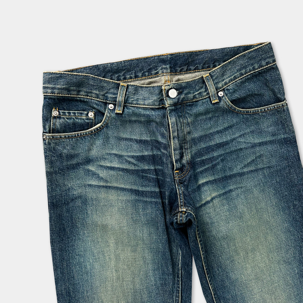 A pair of well-worn blue jeans with visible signs of use, including creases and folds in the fabric.