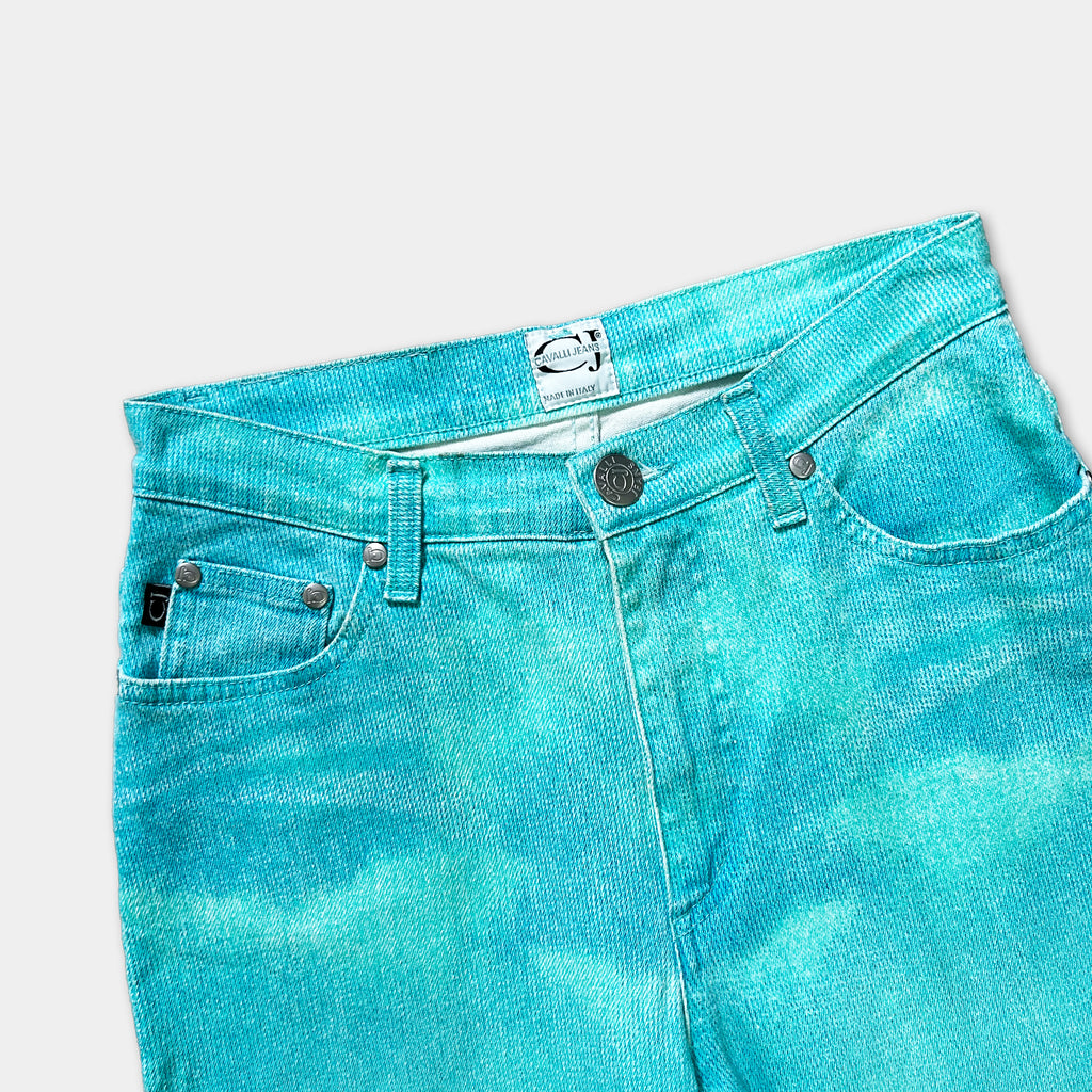 A pair of turquoise-colored jeans with a label on the waistband.