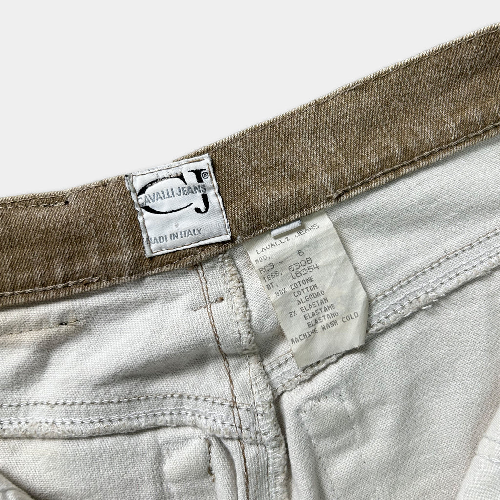 a close-up view of a pair of white jeans with a label attached to the waistband, indicating the brand and details of the jeans.