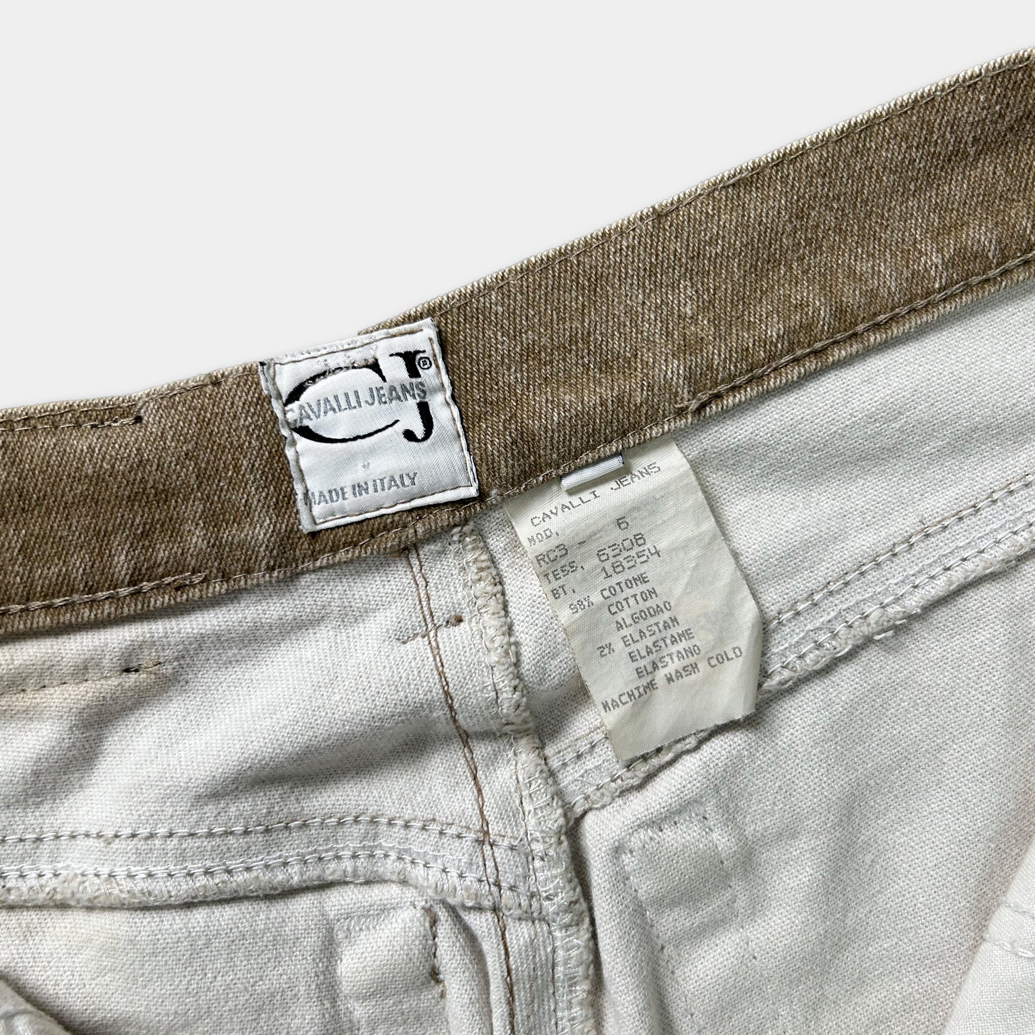 a close-up view of a pair of white jeans with a label attached to the waistband, indicating the brand and details of the jeans.