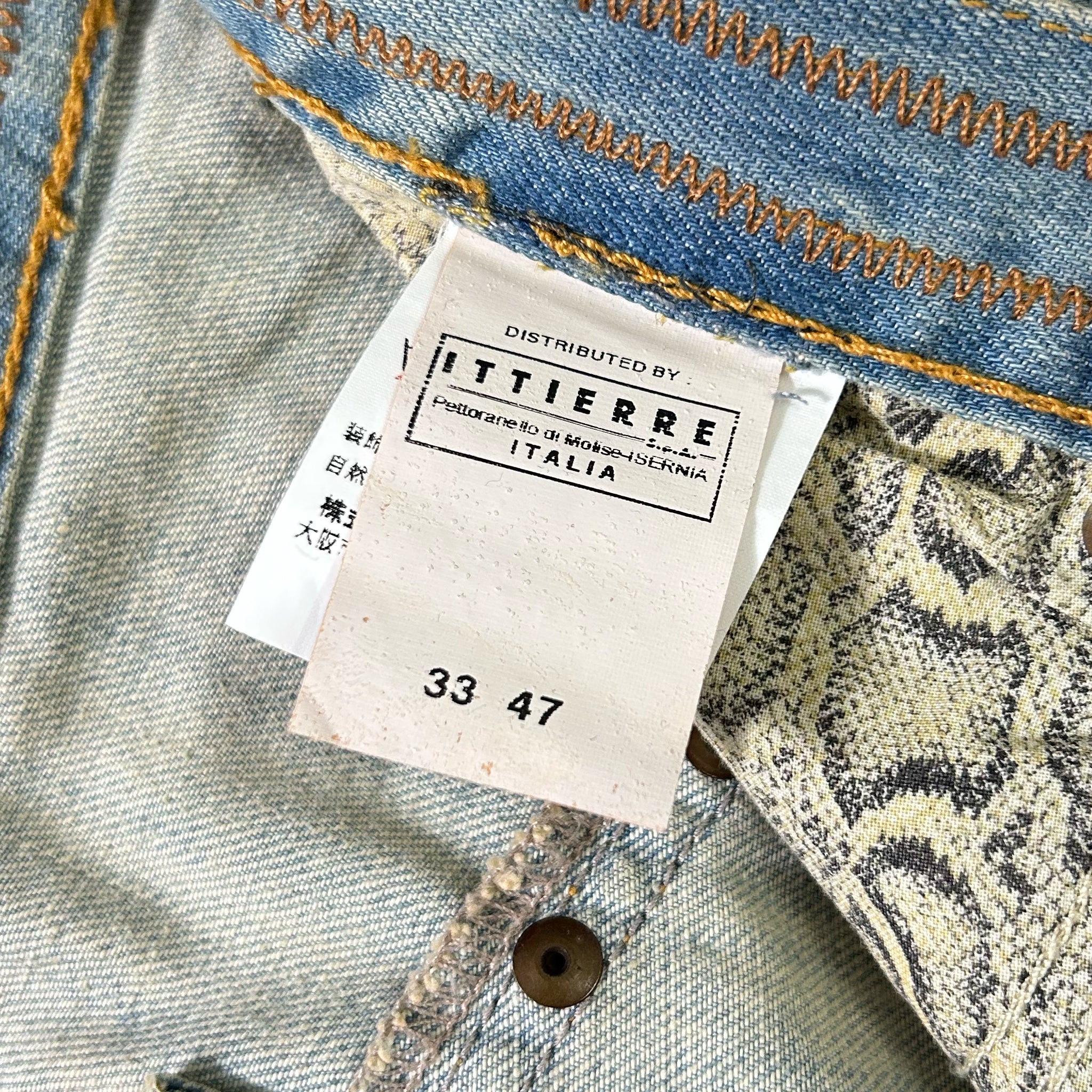 a close-up view of a denim fabric, with a label attached to it. The label is from a brand called "ITTIERE" and displays the number "33 47".