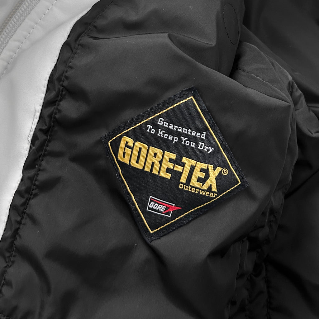 a close-up view of a black and white jacket, with a prominent "GORE-TEX" patch on the fabric.