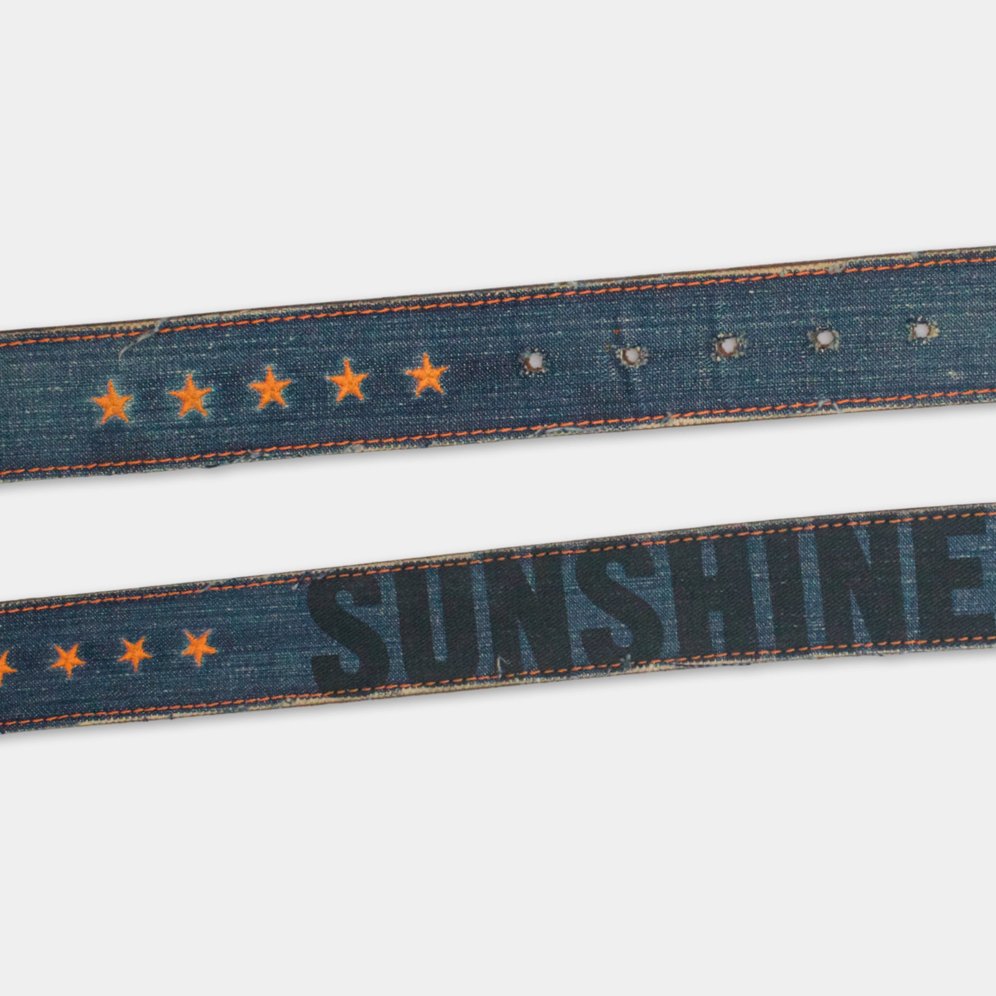 a pair of blue denim belts with orange stars and the word "SUNSHINE" printed on them.