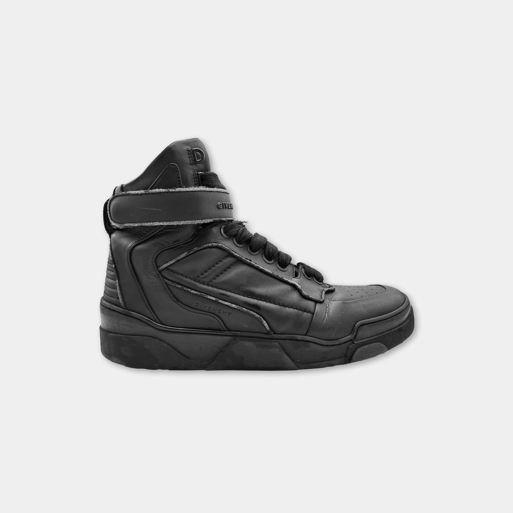 A black high-top sneaker with a strap on the side.