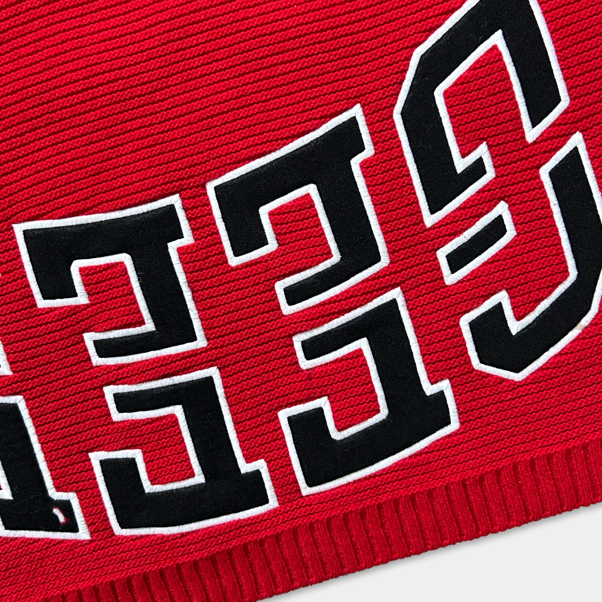 A close-up view of a red fabric with bold black text in a stylized font.