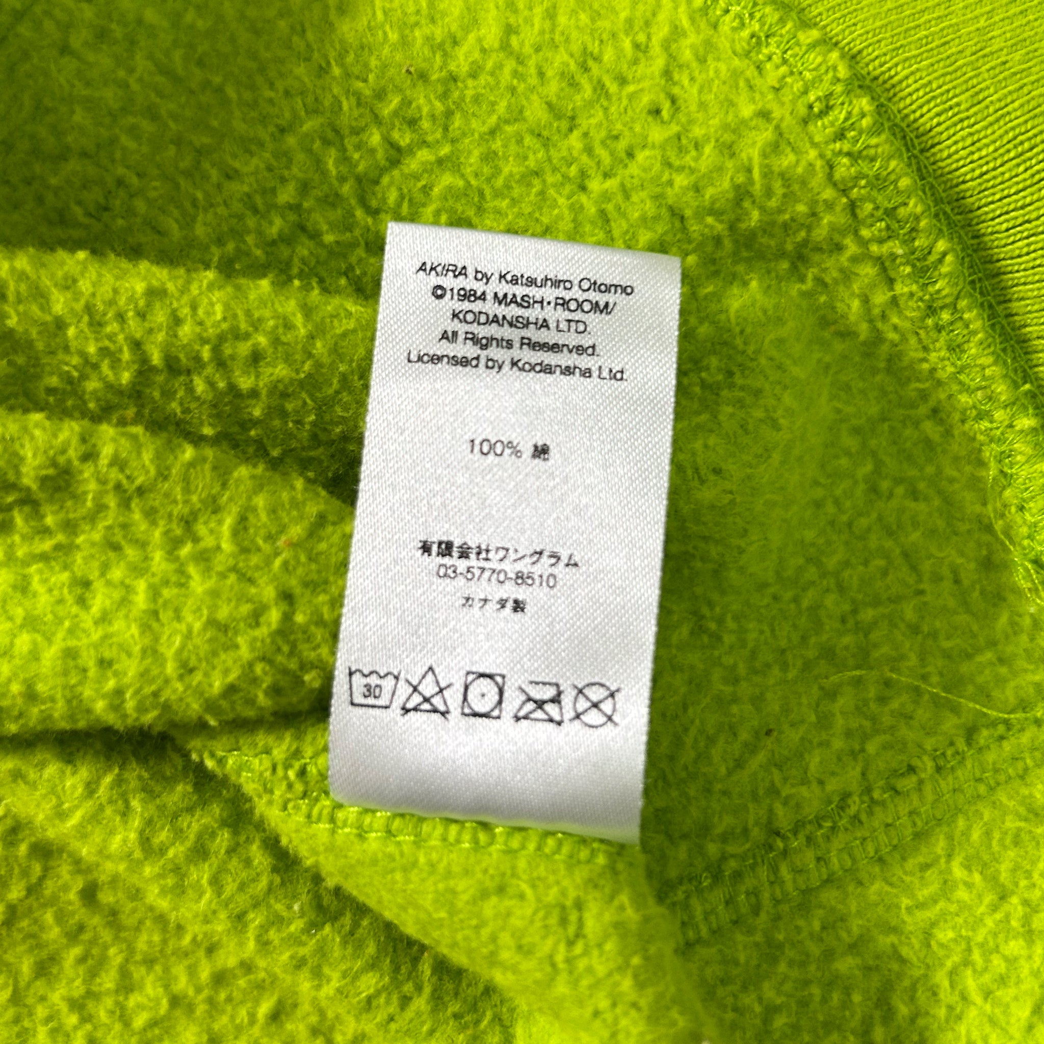 a close-up of a white label with text and symbols on a bright green fabric background.