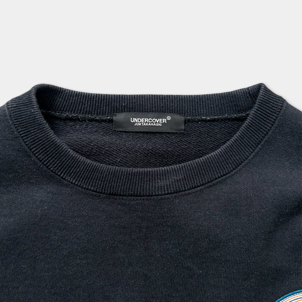 a close-up view of a black sweater with a label on the collar.