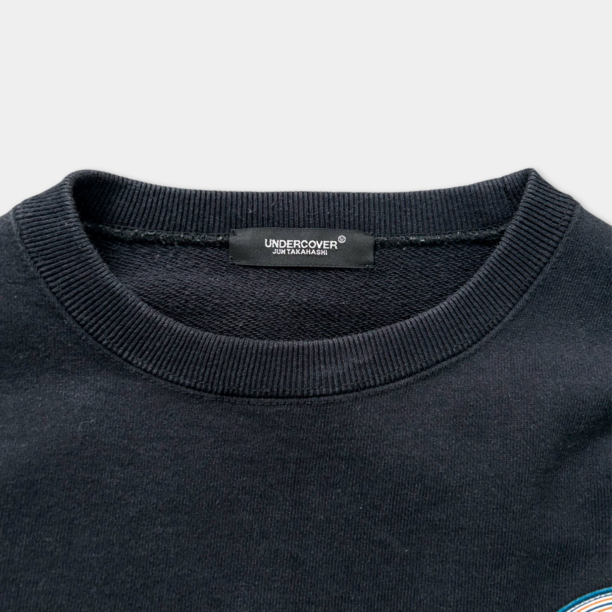 a close-up view of a black sweater with a label on the collar.