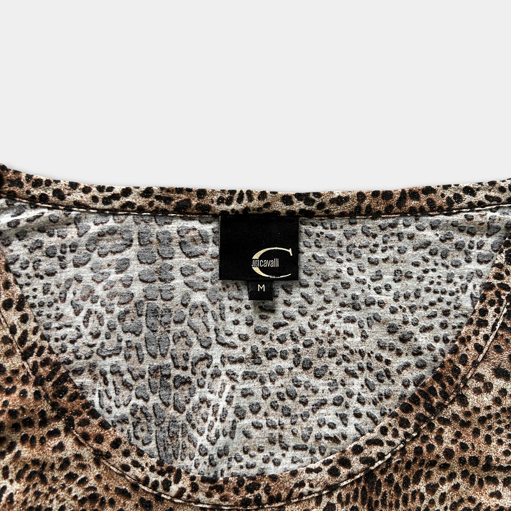 a close-up view of a leopard print top, with a label attached to the collar.