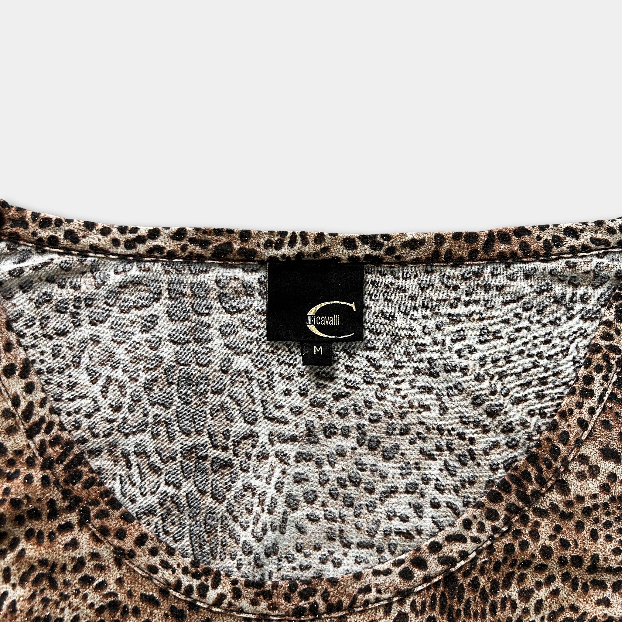 a close-up view of a leopard print top, with a label attached to the collar.