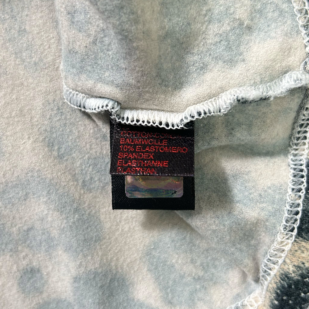 a close-up view of a fabric label with text on it, placed on a fabric with a gray and white pattern.