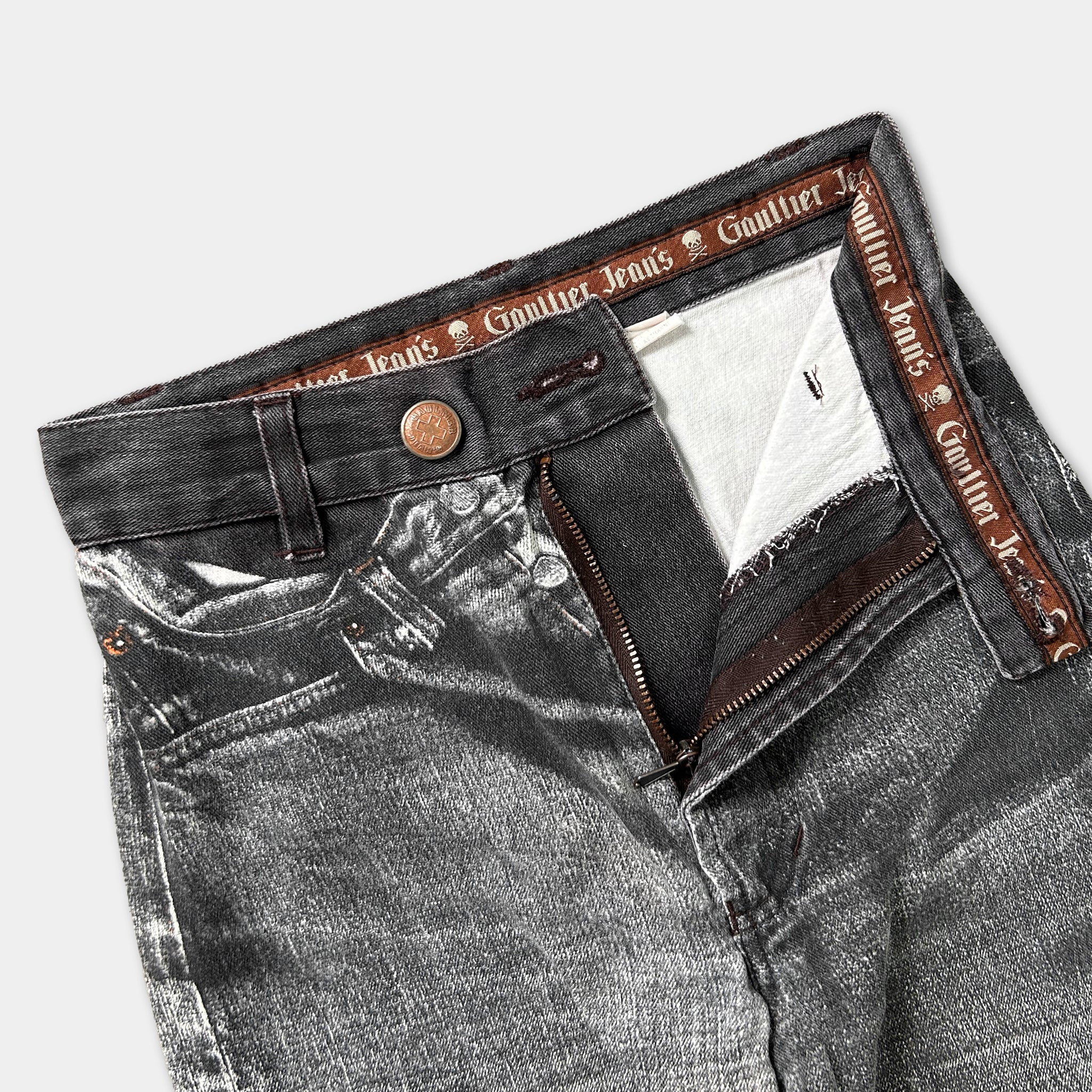 A pair of black jeans with a distinctive zipper detail and a label that reads "Gaurier Jeans" printed on the waistband.