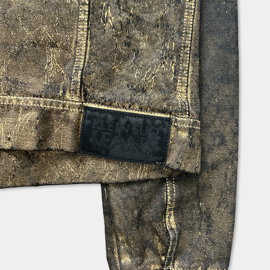 A close-up view of a piece of clothing with a black label on it, featuring a gold-colored design.