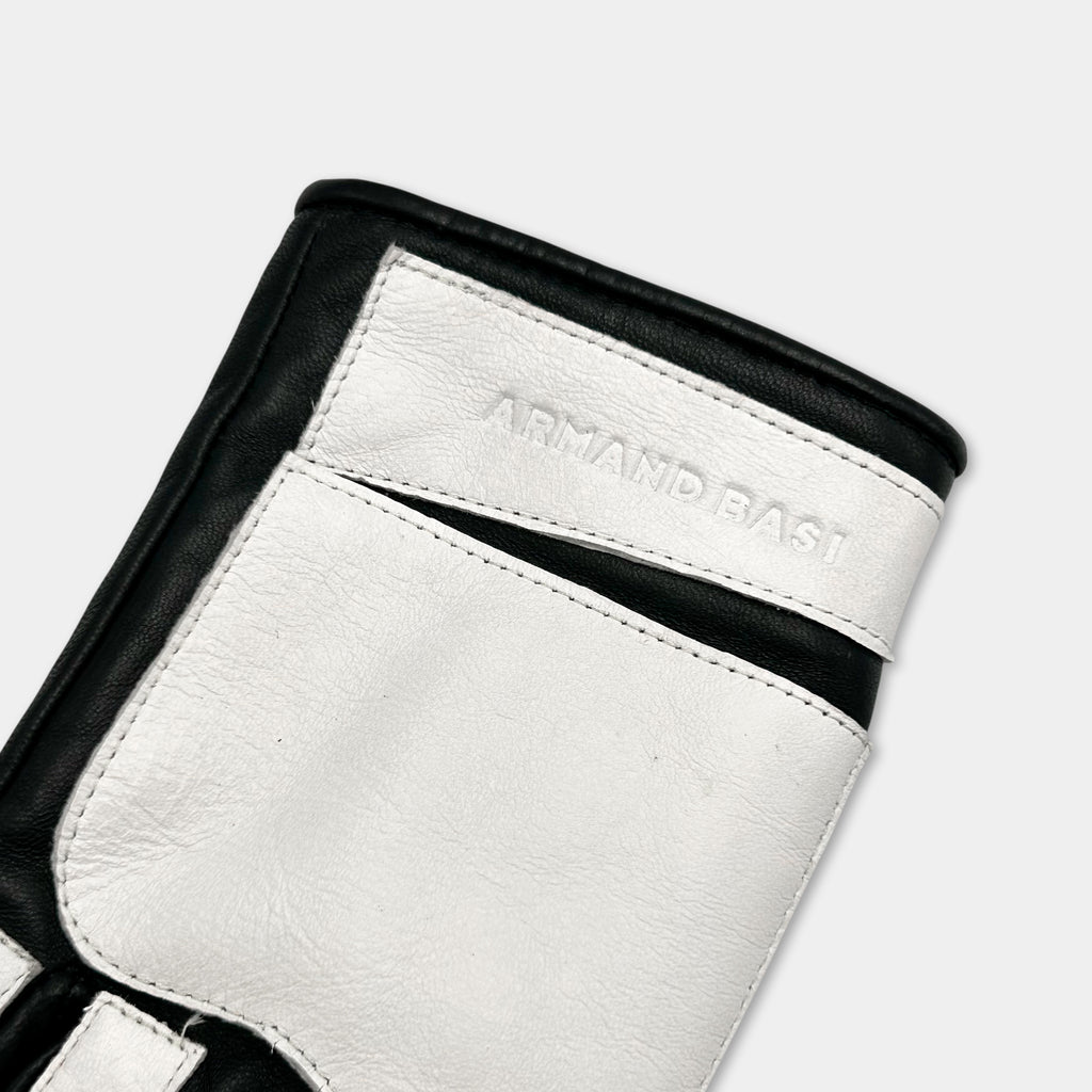 A close-up view of a black and white glove with the brand name "ARMAND BASI" printed on it.