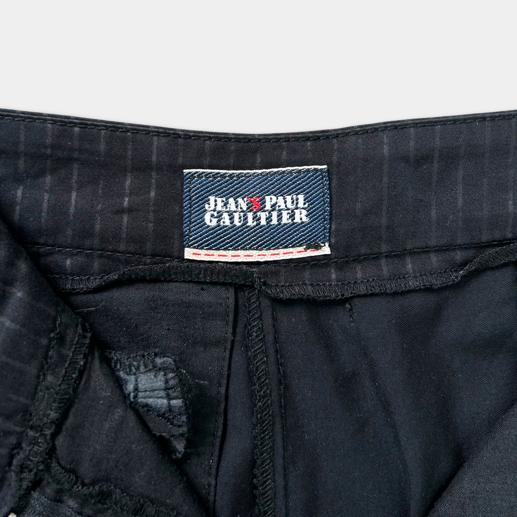 A close-up view of a black label on a pair of black pants, displaying the brand name "Jean Paul Gaultier".