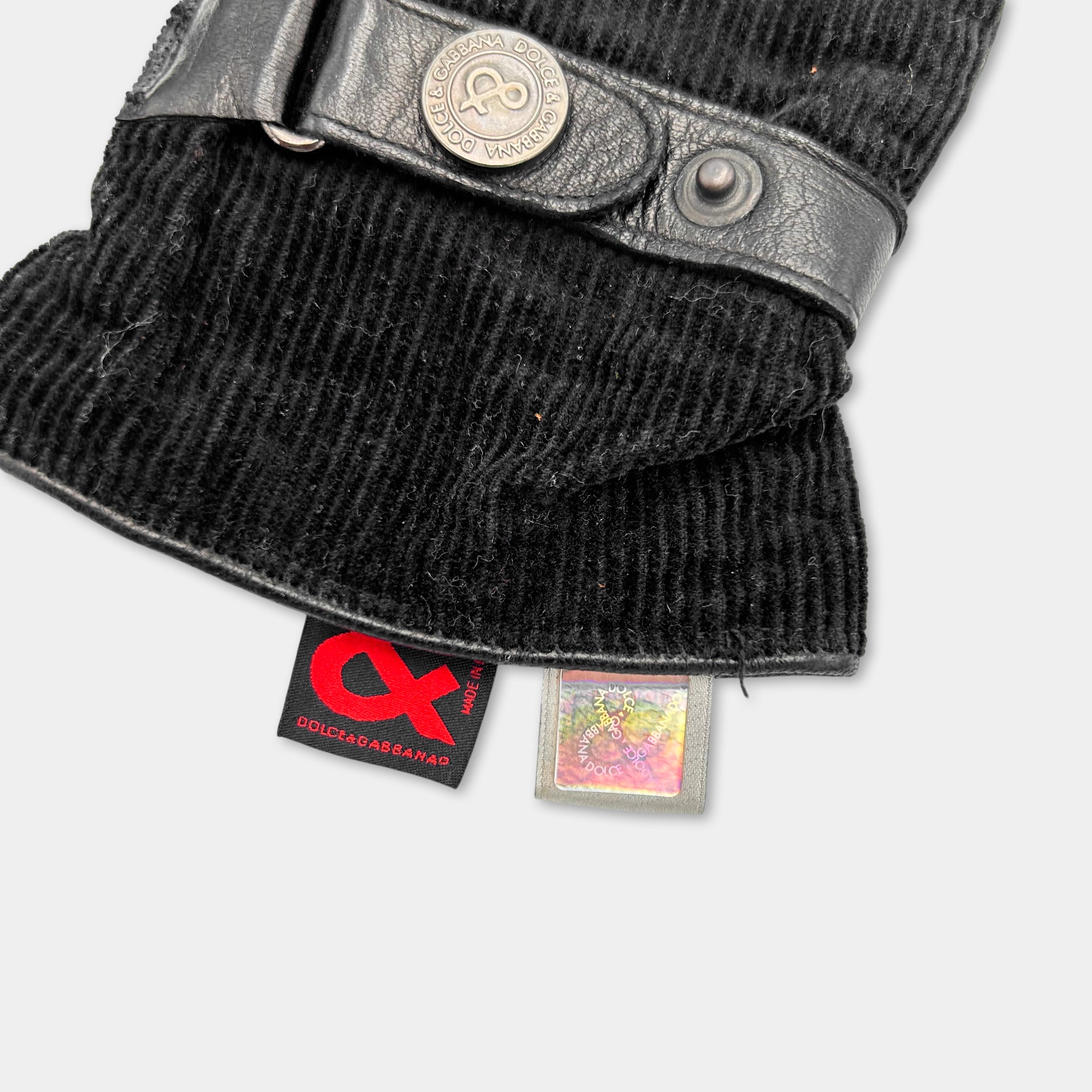 a close-up view of a black glove with a leather strap and a red and black label attached to it.