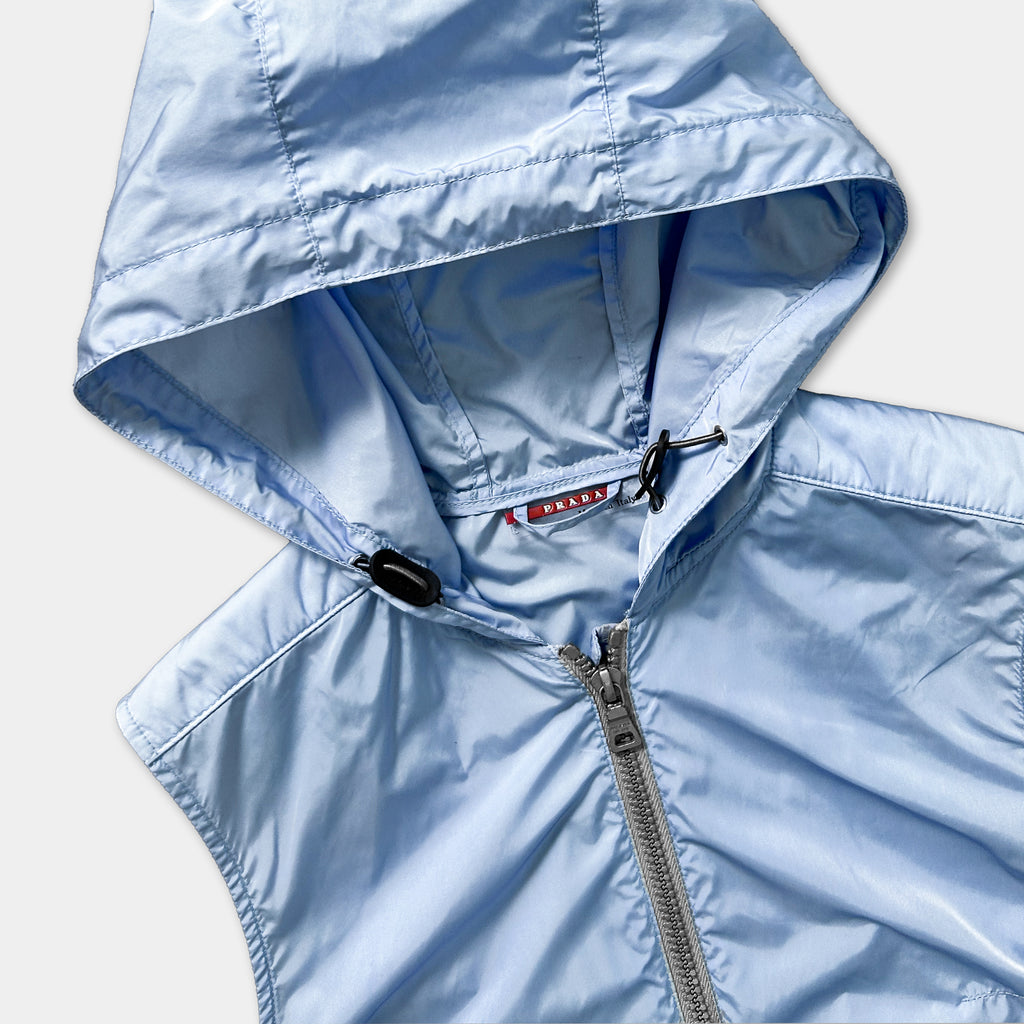 A light blue hooded jacket with a zipper and a red logo on the chest.