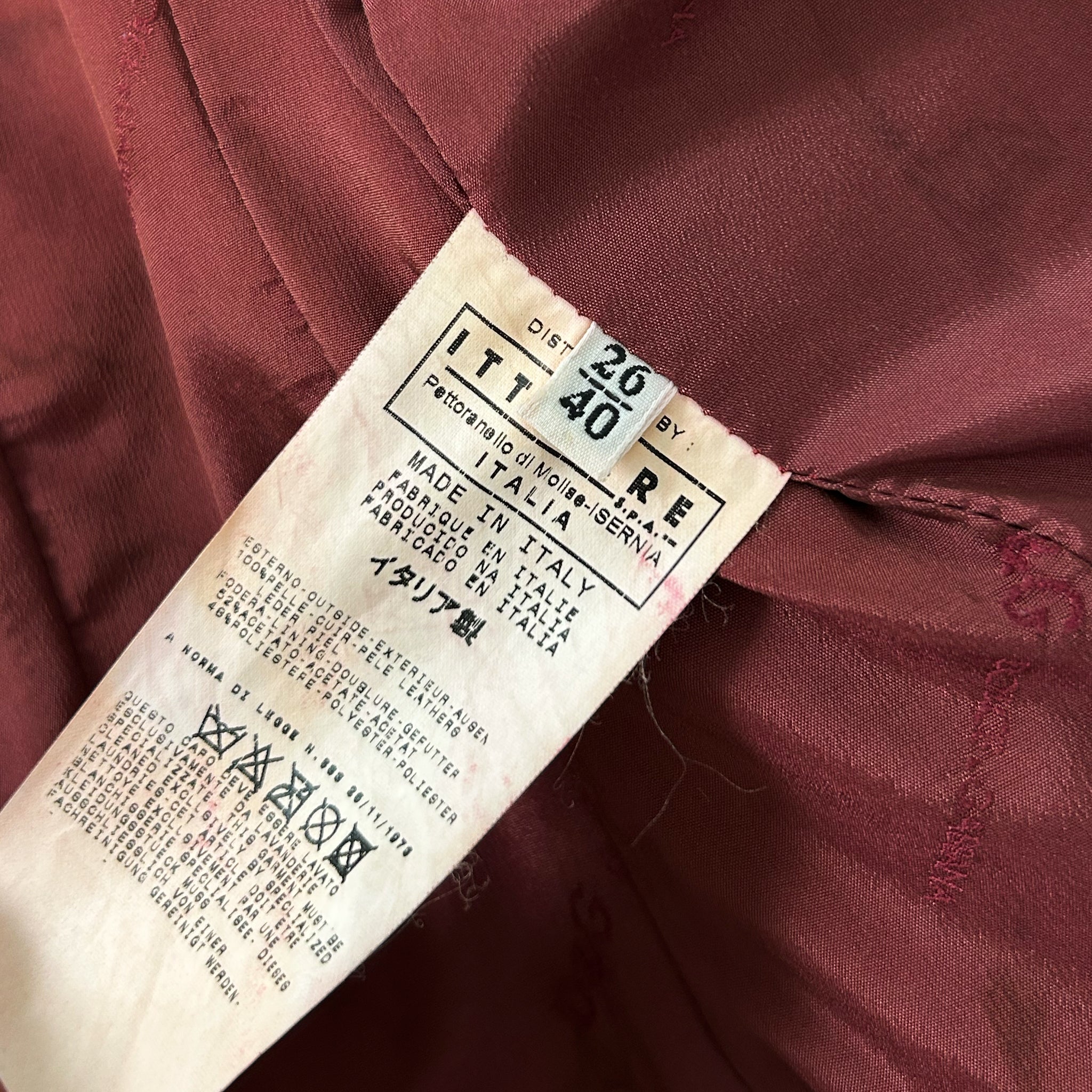 a close-up view of a red fabric, possibly a piece of clothing, with a label attached to it. The label appears to be a label or tag, providing information about the fabric, such as its origin or production details.