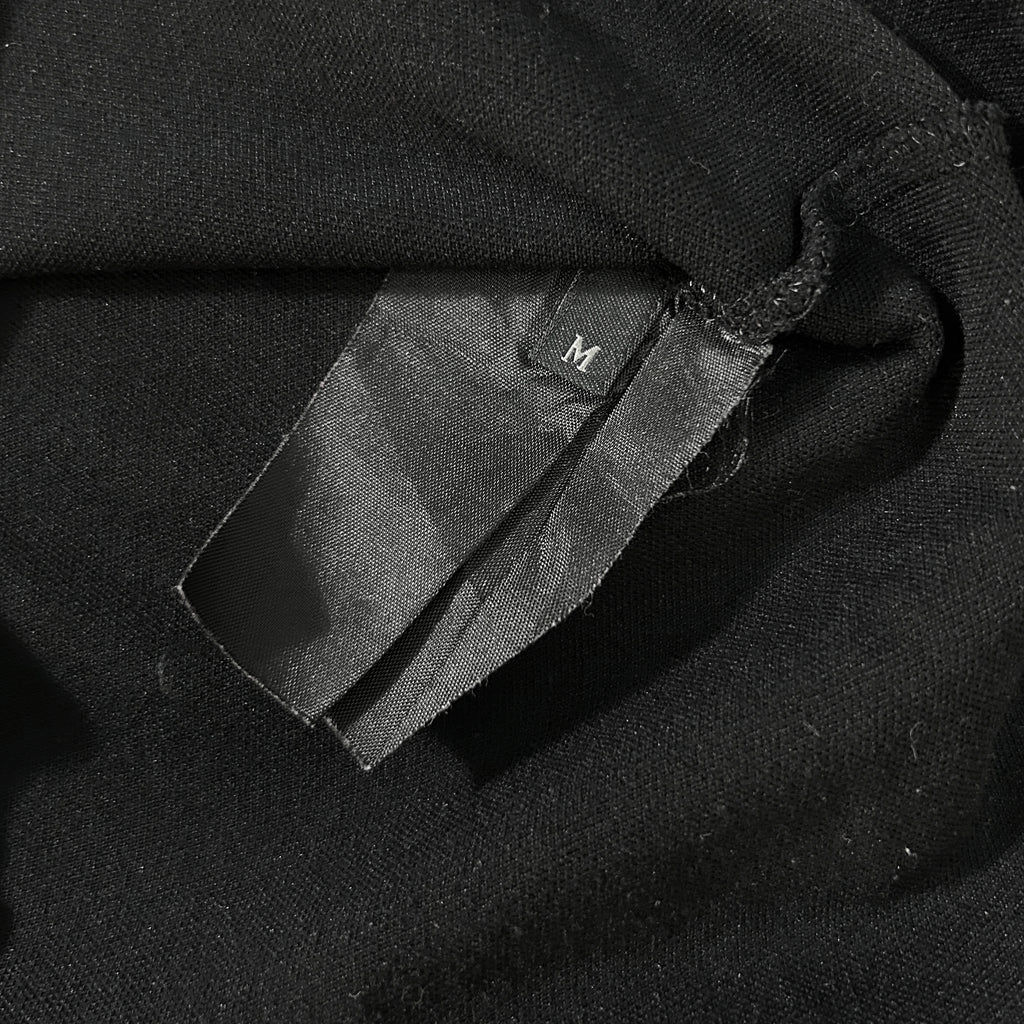 A close-up view of a black fabric, possibly a shirt or garment, with a small label or tag attached to it.