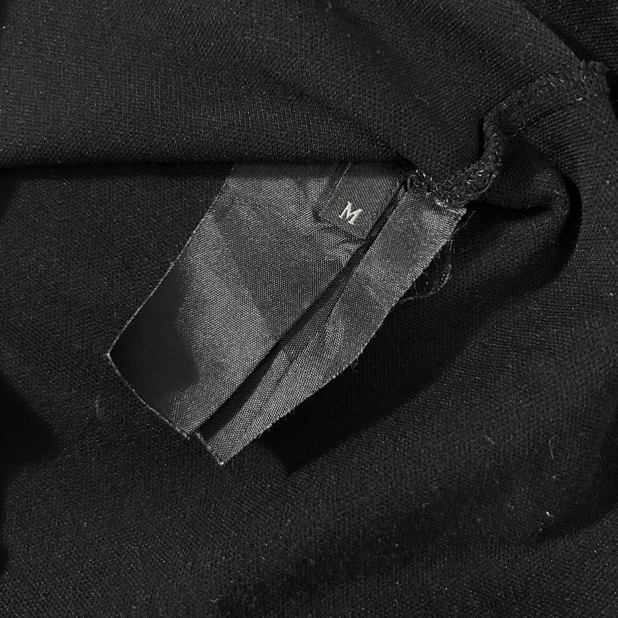 A close-up view of a black fabric, possibly a shirt or garment, with a small label or tag attached to it.