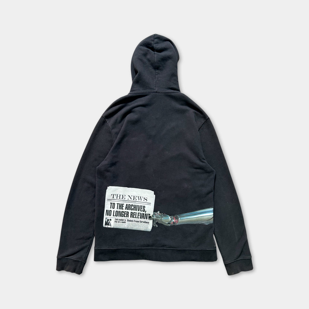 A black hooded sweatshirt with a graphic design on the back, depicting a newspaper headline and a bullet point.