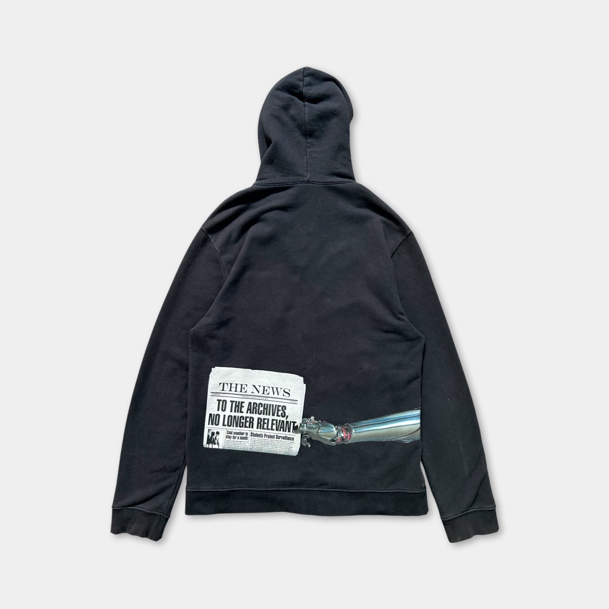 A black hooded sweatshirt with a graphic design on the back, depicting a newspaper headline and a bullet point.