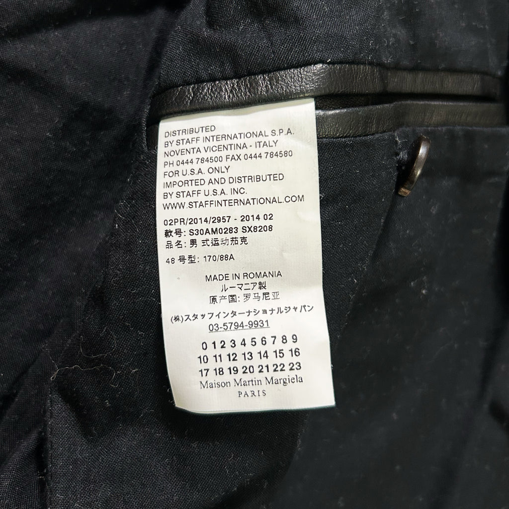 a close-up of a label on a black fabric, likely a piece of clothing, with text in multiple languages.
