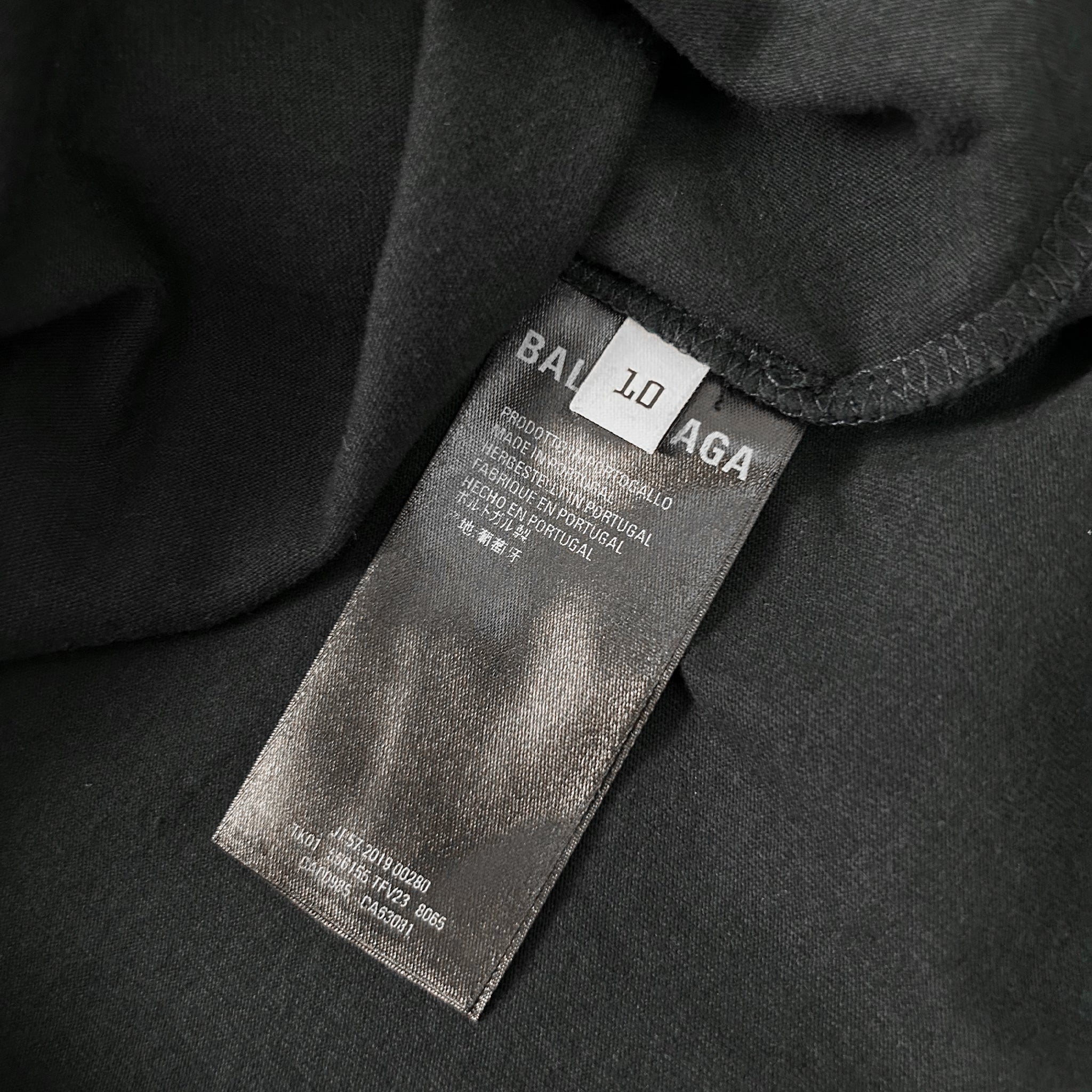 a close-up view of a black fabric with a white label attached to it. The label appears to be a garment tag or label, possibly from a clothing brand.