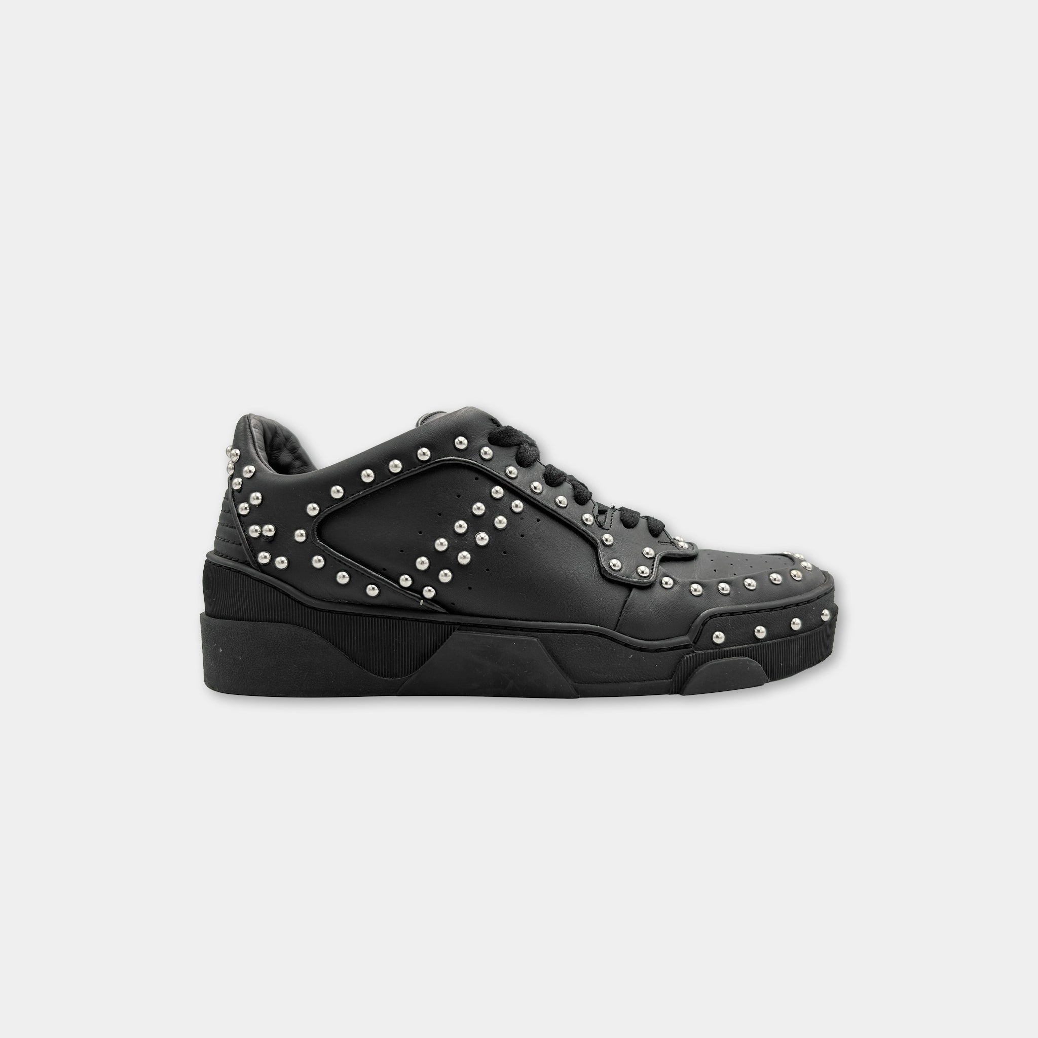 A black sneaker with silver studs on the side and sole.