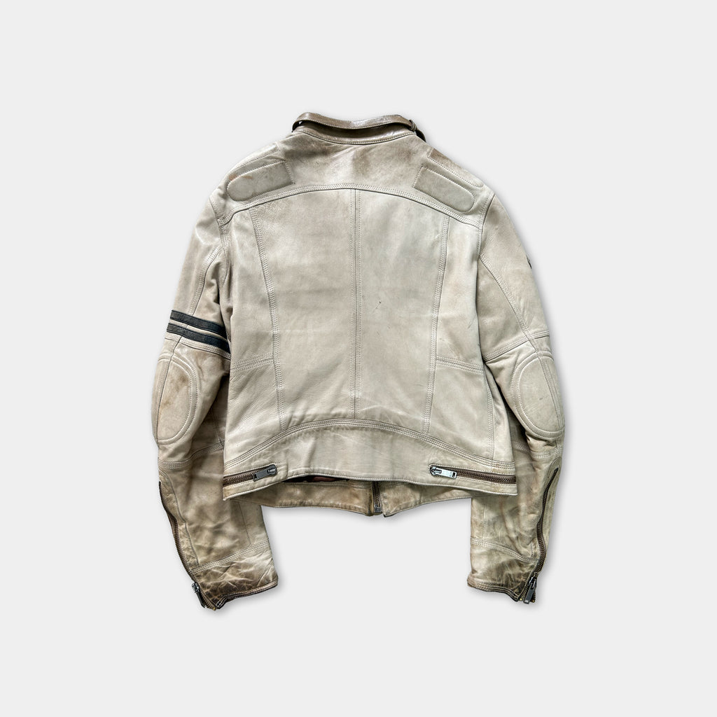 A worn, light-colored leather jacket with a collar and two pockets, hanging against a plain background.