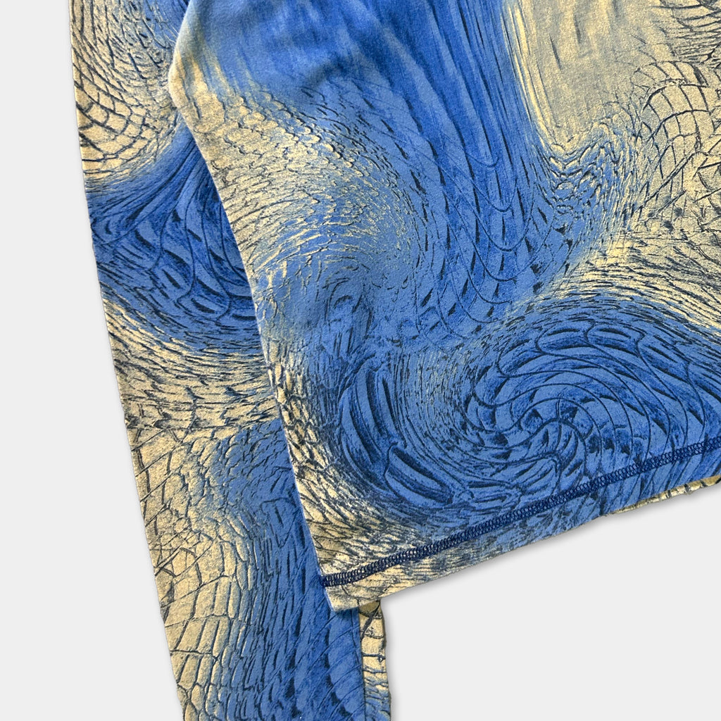 a close-up view of a fabric with a blue and gold pattern, resembling the scales of a fish or a dragon.