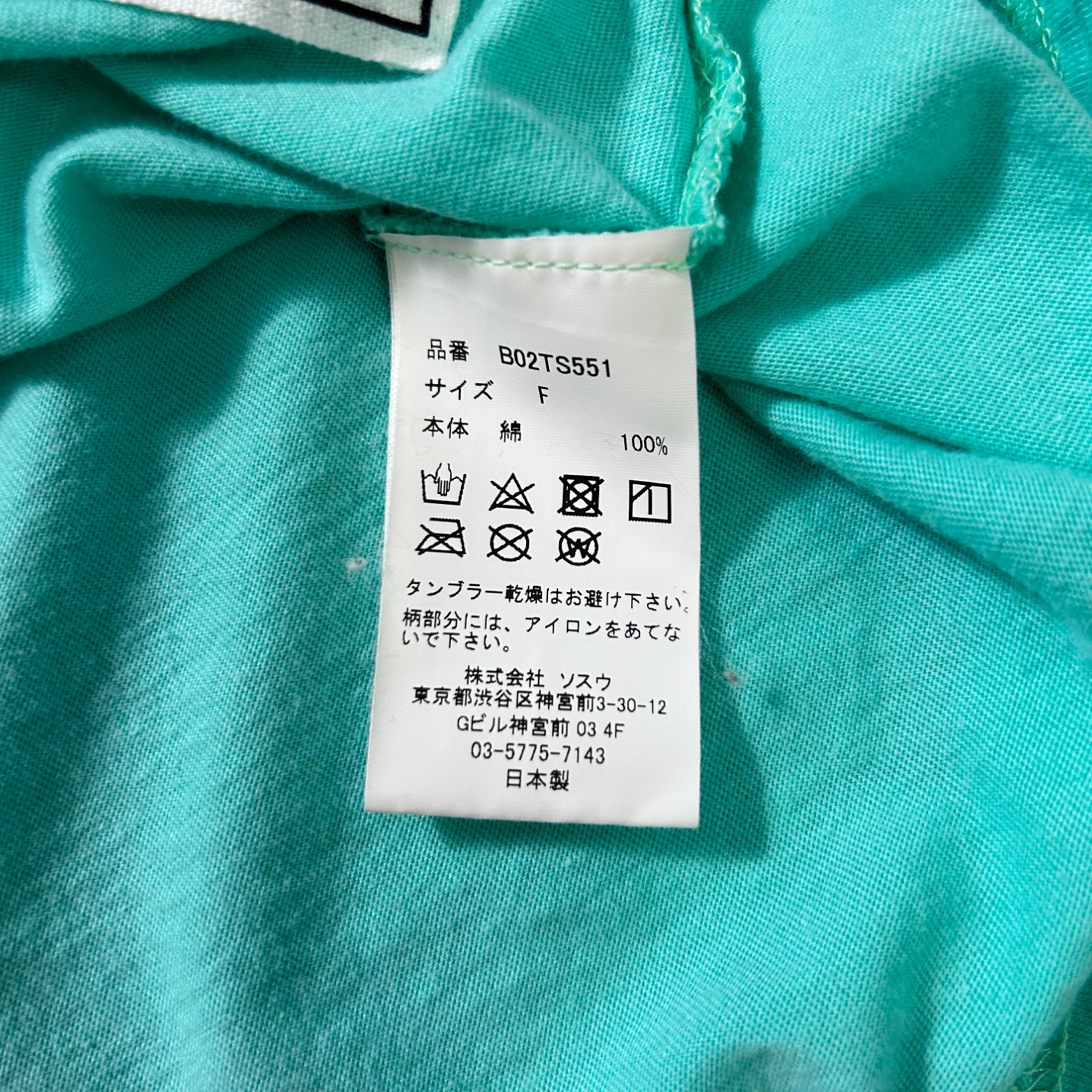 a close-up view of a white label with text and symbols on a turquoise fabric.